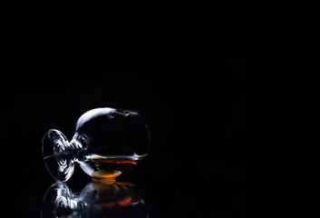 glass of snifter with whiskey on a black background