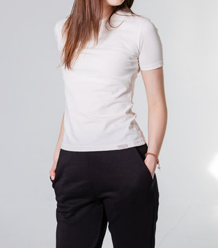 Young girl wearing blank t-shirt and and sport pants. Gray wall background shadow light from the window with copy space for your text message or promotional content