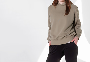 Young girl wearing blank sweatshirt and and sport pants. Gray wall background shadow light from the window with copy space for your text message or promotional content