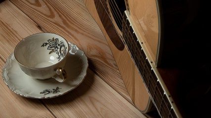 Kompozycja filiżanki i gitary na tle sosnowych desek. © Mariusz