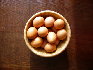 brown eggs in a bamboo bowl on a wooden table in the sunlight