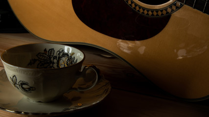 Kompozycja filiżanki i gitary na tle sosnowych desek. © Mariusz