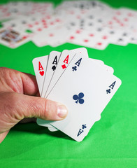 man plays cards on the green table - poker of aces in the player's hand