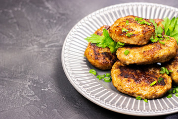 fresh meat fried cutlets with greens on a plate, close-up. brutal men's food on a wooden stand on a black stone table