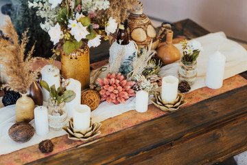 Bouquet of white flowers in a vase, candles on vintage table, wedding home decor on a table.  Living room interior and home decor concept.