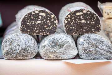 Large portion of a traditional Romanian salam de biscuiti or chocolate salami with biscuits and sugar biscuits, displayed for sale on a table at a street food market

