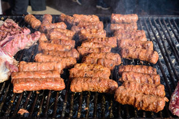Grilled meat rolls called Mici or Mititei, traditional fresh Romanian barbeque grill food cooked on the barbeque at a street food market
