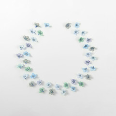 Creative flower layout made with aqua colorful daisys in shape of wreath on white pastel background. Spring awakening concept. Abstract beauty mock up.