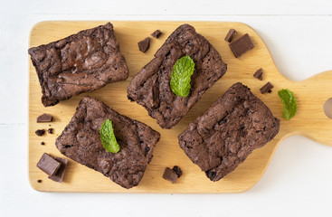 Top view of chocolate brownies on wooden board on white table, homemade sweet and dessert concept