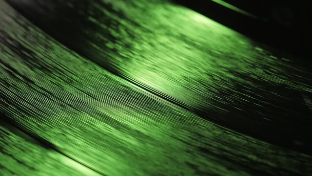 A fragment of a rotating vinyl record in the green rays of a disco. Audio equipment for dj. The moment of a spinning vinyl plate. Turntable vinyl record player