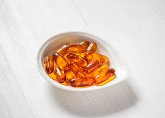 Fish oil capsules on white wooden background