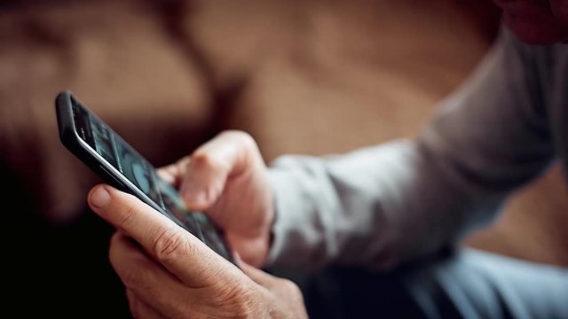 an elderly man with a smartphone in his hand, ordering goods from an online store with delivery during quarantine