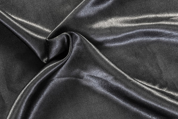 Delicate smooth soft black silk fabric background. Abstract crumpled satin texture. Glossy textile.