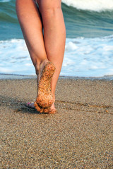Female legs on the sea beach, footprints in the sand, vacation and travel concept.