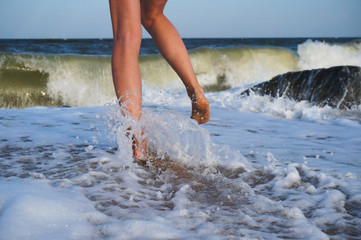 Female legs on the sea beach, footprints in the sand, vacation and travel concept.