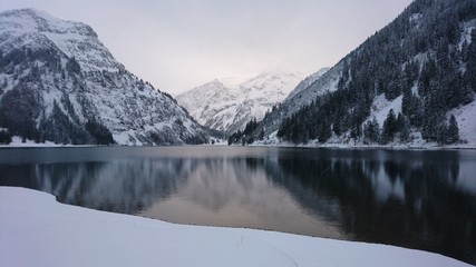 Fototapeta premium Vilsalpsee an einem ruhigen Tag umgeben von Schnee