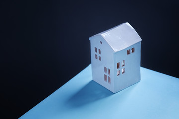 Bright, color and colorful shot of a cute cozy house on a blue surface on a dark background. View from above - 45 angle view. Concept - stay at home. Empty space for text on the left