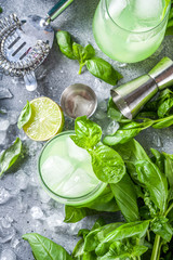 Basil smash gin alcoholic cocktail. Long alcohol drink recipe with fresh basil leaves and limes, grey stone background copy space