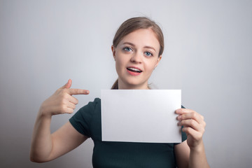 Fototapeta premium Smiling young Caucasian woman girl holding blank white paper sheet with copy space