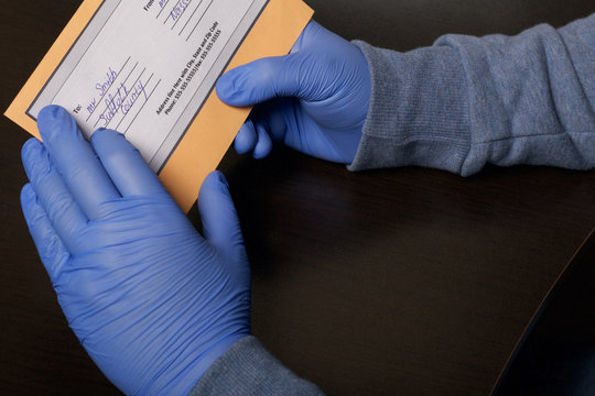 Delivery of correspondence during the period of self-isolation. A man in rubber gloves holds a delivered letter in his hands. Close-up shot.