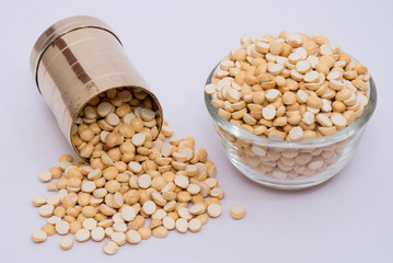 Group of a nutritious roasted gram in a bowl with brass measuring jar on a white background