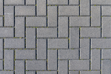 Concrete paving stones in grey during midday noon sunlight laid out in regular pattern texture