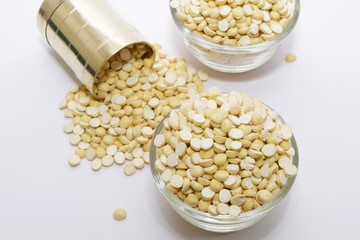 Group of a tasty roasted gram in a bowl with brass measuring jar on a white background
