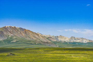 rocky ridge on horizon in mountain valley, green slopes of gentle hills, beauty of nature for relaxation and meditation