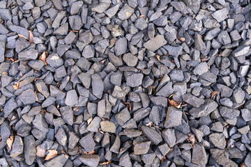 Granite gravel with some dry brown leaves in between texture