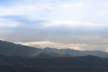 mountain valley under cloudy sky, rock ridge on horizon, hiking in  mountains, rest and meditation in nature