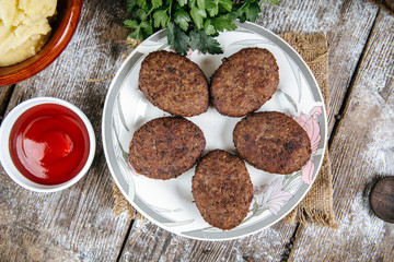 Top view on delicious roasted cutlets on a plate on the wooden table with red sauce, horizontal