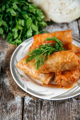 Side view on a dish of eastern european cuisine golubtsy stuffed cabbage leaves with meat, with sour cream and carrot, vertical