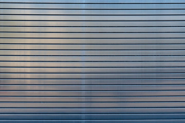 Stainless steel overhead door reflecting midday sunlight texture