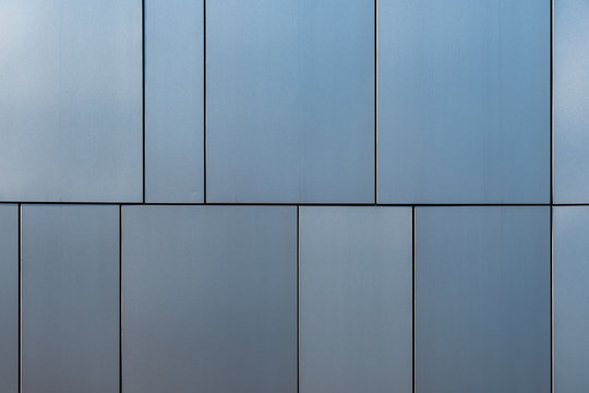 Stainless steel facade cladding shining in different grey and blue tones building texture