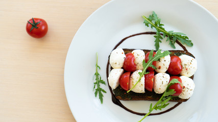 sandwich with mozzarella cheese and cherry tomatoes on a plate. Top view