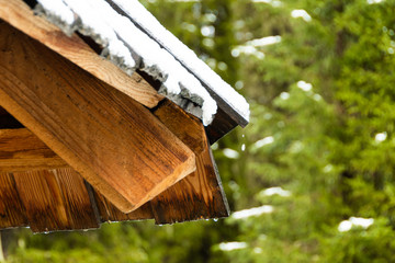 snow on wooden house, icing on roof due to snowfall and melting ice