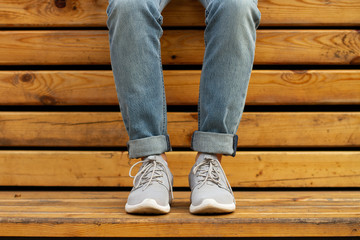Woman sits on wooden bench in blue jeans