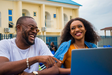 two african couple having a nice time in a park feeling happy about what they saw on their laptop