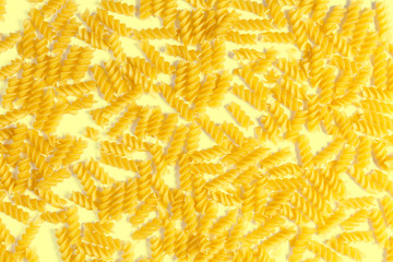 raw fusilli pasta on a yellow background. Top view.