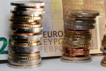 Stacked Euro coins in front of a 200 Euro banknote. EURO writing on bill in yellow