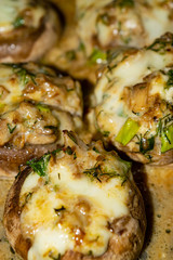 Mushrooms baked in the oven with cheese, green onions and dill. Close up.