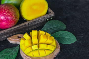 fresh mangoes in a drawer and half a mango on a chopping board close-up. mango on a wooden background.