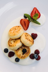 Cheesecakes with berries and sauce close-up on a plate. Cheese pancakes with berries and grape sauce.