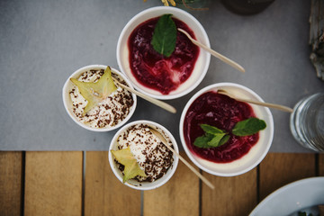 Ice cream with jam and fruit in paper cups.
