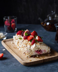 Meringue roll with berries on a plate on a dark background.