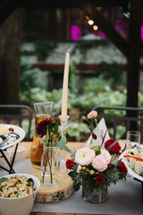 Roses in glass vases on wooden slices on a table at a banquet.