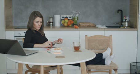 Woman working with papers sitting in kitchen at home.