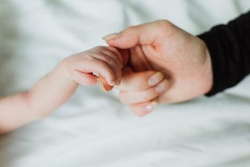 Mom holds the hand of a newborn.