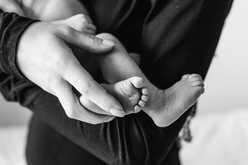 Close-up of the legs of a newborn in the hands of mom. Black and white photo of the legs of a newborn in the hands of her mother.