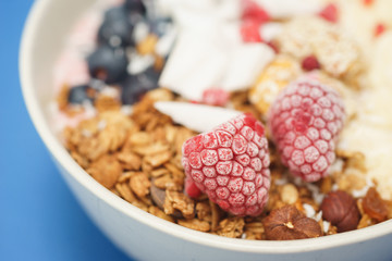 Handmade Bowl healthy tasty breakfast of yogurt, smoothie with granola, nuts, bananas and berries